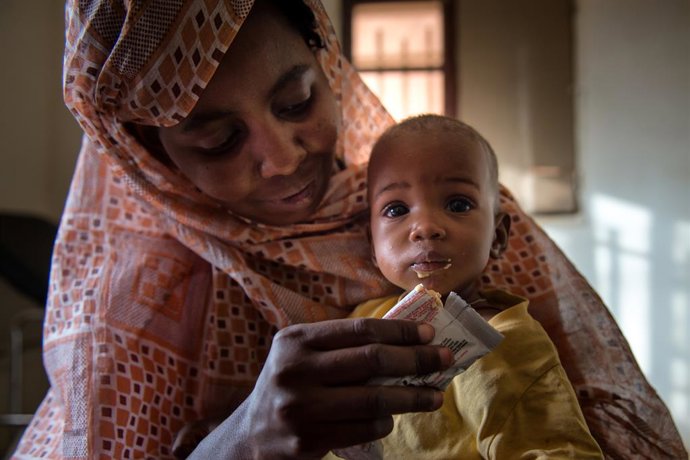 Uma mãe alimenta uma criança com um alimento terapêutico pronto para consumo.