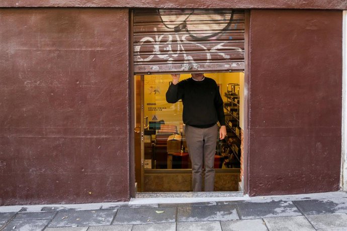Archivo - Un autónomo echando el cierre de su negocio tras su jornada laboral