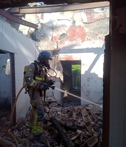 Un bombero trabajando en el interior de la vivienda incendiada