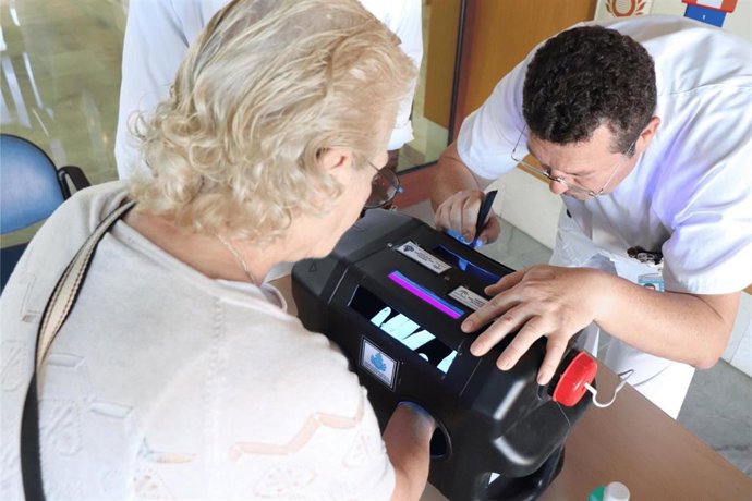Un médico del hospital enseña a una paciente los efectos de la higiene de manos con una lámpara de luz ultravioleta.