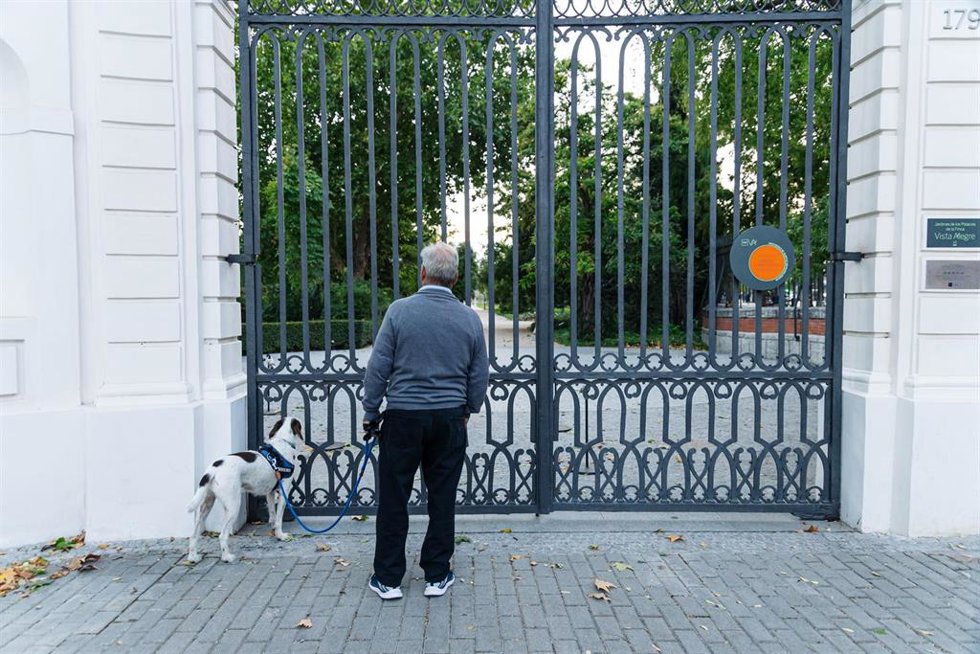 Archivo - Hombre con perro mira el interior de un parque cerrado con el cartel de protocolo de alertas metereológicas, a 17 de octubre de 2023, en Madrid (España). La Agencia Estatal de Meteorología (Aemet) ha activado la alerta naranja por fuertes rachas