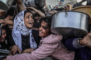 Archivo - Un grupo de niños palestinos desplazados espera para recibir alimentos en Gaza.