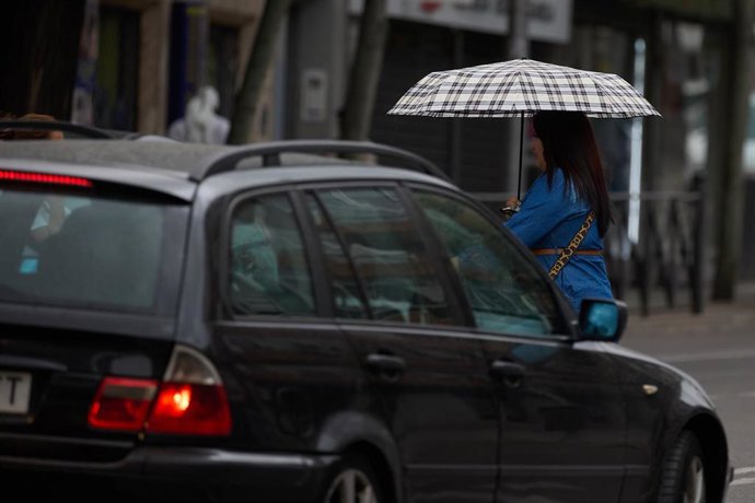 Archivo - Una mujer se protege de la lluvia con un paraguas, a 8 de junio de 2024, en Madrid (España).