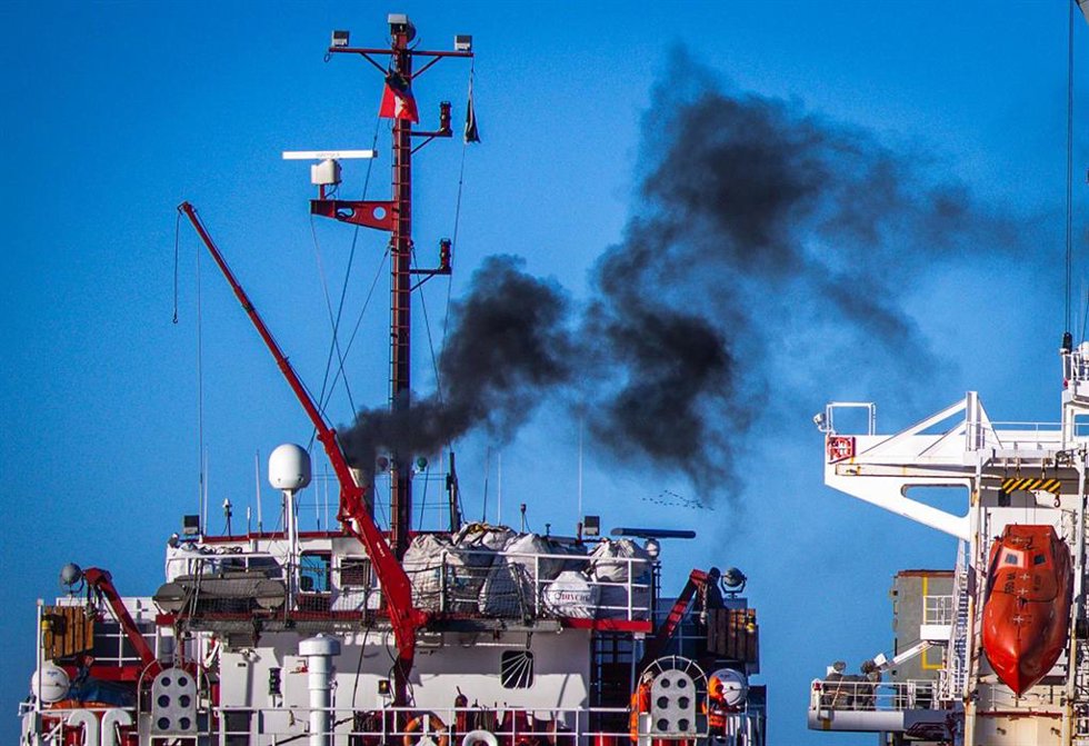 Archivo - Una densa columna de humo negro se eleva desde la chimenea de un buque de carga al entrar en el puerto. 