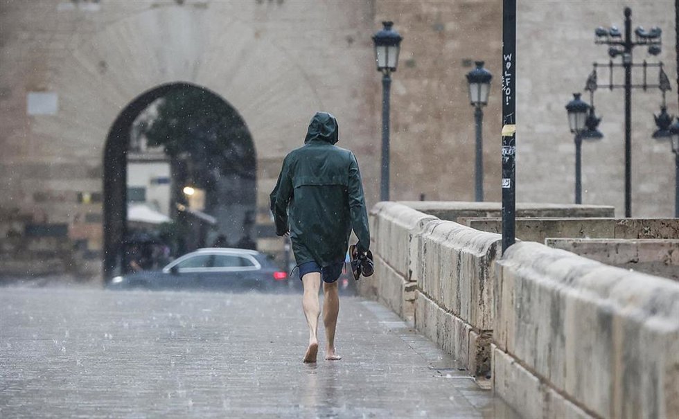Archivo - Una persona camina bajo la lluvia.