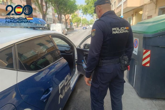 Archivo - Agente de la Policía Nacional frente a un coche patrulla.