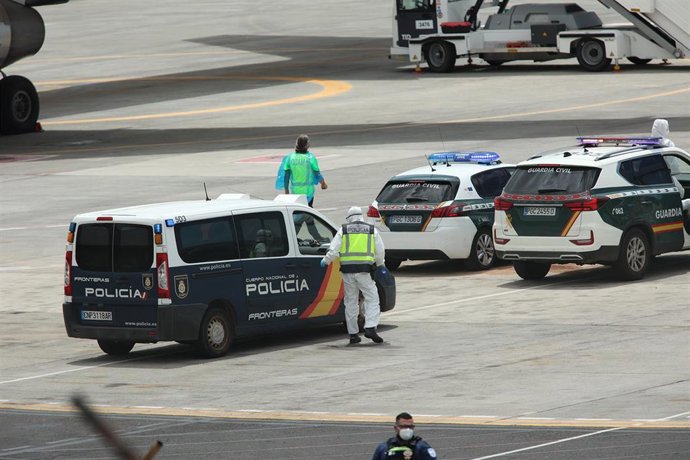 Policías nacionales, guardias civiles y militares de la UME vestidos con monos EPI y mascarillas coordinan a los viajeros evacuados del crucero MV Hondius, en el aeropuerto de Tenerife Sur, a 10 de mayo de 2026, en Tenerife, Islas Canarias (España). El op