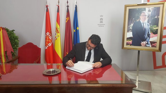 El portavoz del Grupo Municipal Socialista en el Ayuntamiento, Ginés Ruiz Maciá, firmando en el libro de condolencias por el fallecimiento del alcalde de Murcia, José Ballesta