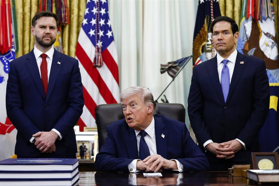El vicepresidente de EEUU, JD Vance (izq.), y el secretario de Estado, Marco Rubio (der.), flanquean al presidente del país, Donald Trump (centro), mientras este habla con los medios de comunicación en el Despacho Oval de la Casa Blanca, en Washington DC