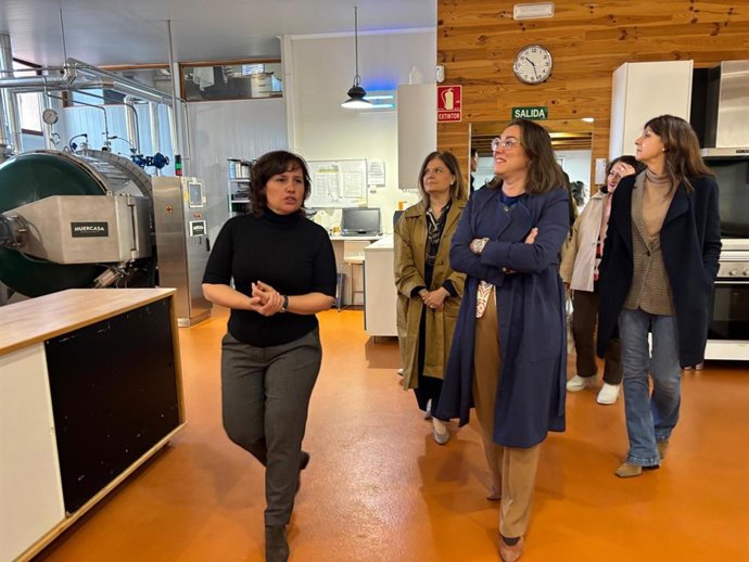 La directora de la empresa 'Cocina de ideas en la naturaleza', situada en la localidad segoviana de Pradera de Navalhorno, Cristina Rueda, muestra sus instalaciones a la consejera González Corral