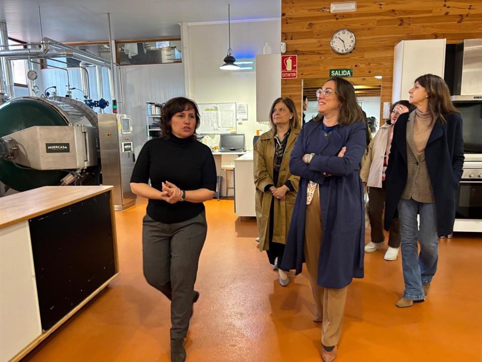 La directora de la empresa 'Cocina de ideas en la naturaleza', situada en la localidad segoviana de Pradera de Navalhorno, Cristina Rueda, muestra sus instalaciones a la consejera González Corral