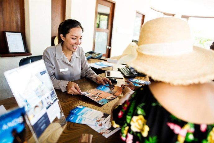 Una recepcionista atiende a una turista.