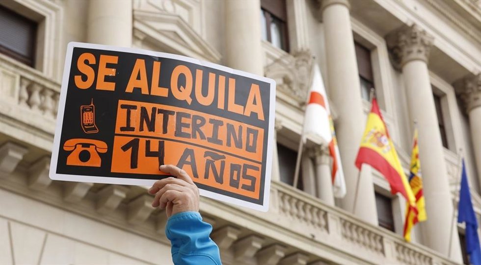 Un trabajador interino se manifiesta en la Plaza de España con una pancarta donde se puede leer "Se alquila, interino 14 años" para protestar contra la contratación temporal de las administraciones públicas