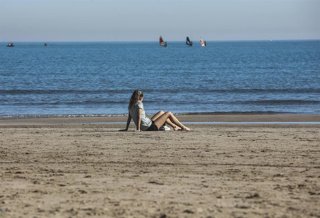 Archivo - Una mujer sentada en la arena de la playa de la Malvarrosa, en Valencia. 