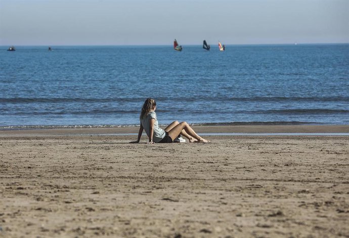 Archivo - Una mujer sentada en la arena de la playa de la Malvarrosa, en Valencia. 