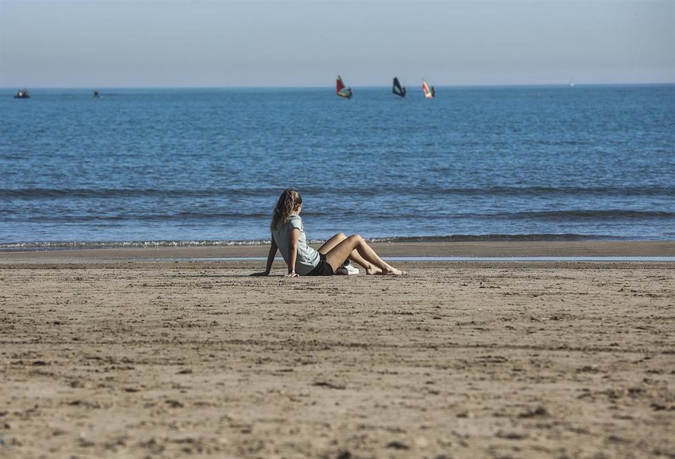 Archivo - Una mujer sentada en la arena de la playa de la Malvarrosa, en Valencia. 