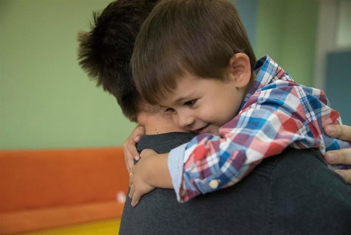 Un niño abrazado a un adulto.
