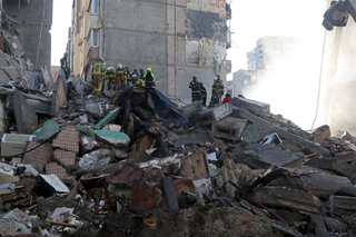 Equipos de rescate del Servicio Estatal de Emergencias retiran los escombros de un edificio de apartamentos de nueve pisos dañado por un ataque con misiles y drones rusos en Kiev, Ucrania