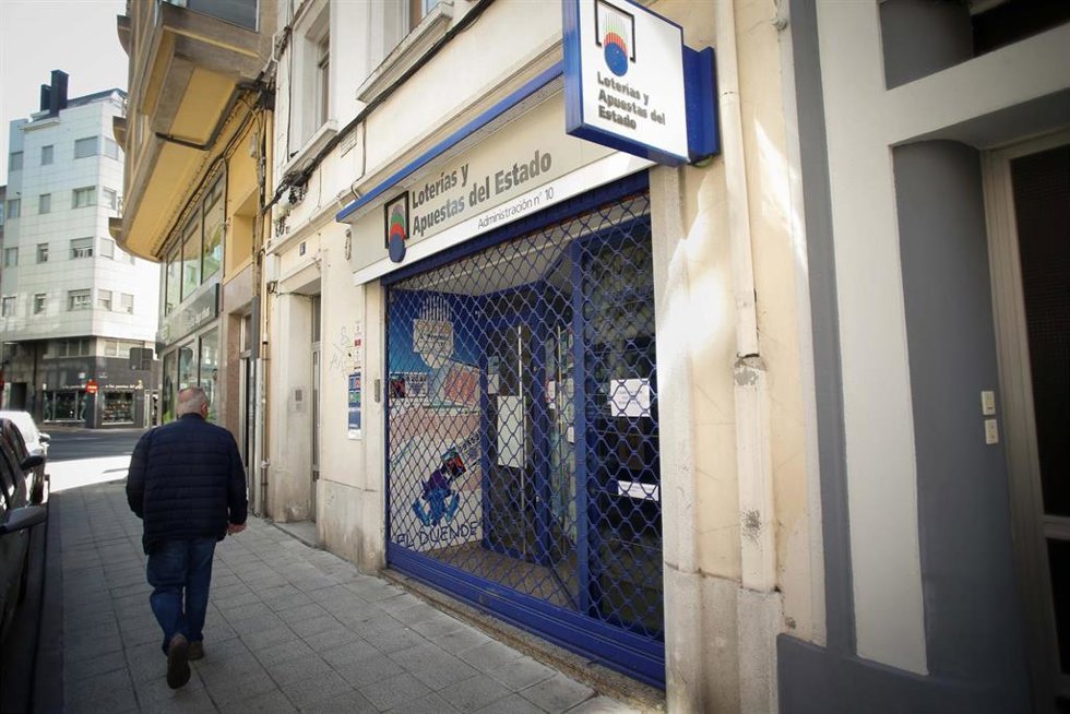 Archivo - Un hombre pasa por una administración de Loterías 