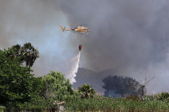 Archivo - Un helicóptero echa agua a una zona afectada por un incendio