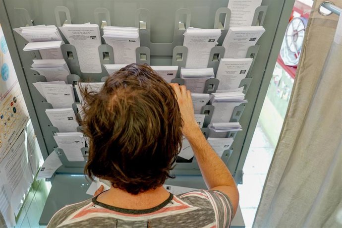 Archivo - Una persona dentro de una cabina electoral para coger su papeleta para votar, en una imagen de archivo