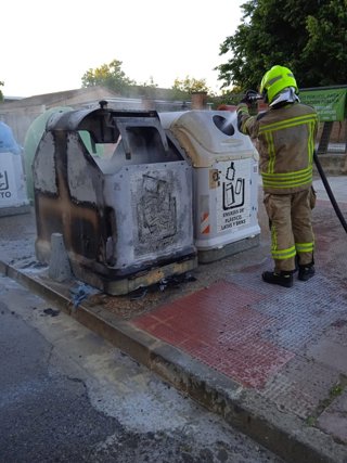 Un bombero aplica agua sobre uno de los contenedores afectados por el fuego este sábado en Huesca.