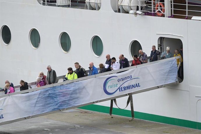 Personal sanitario (con chalecos amarillos) desembarca con pasajeros del crucero 'Ambition', aislado por un brote de gastroenteritis, durante una escala en el puerto de A Coruña.