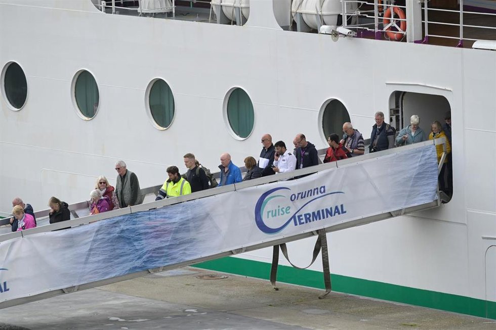 Personal sanitario (con chalecos amarillos) desembarca con pasajeros del crucero 'Ambition', aislado por un brote de gastroenteritis, durante una escala en el puerto de A Coruña.