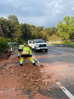 Efectivos de la unidad de Bomberos Forestales de Buñol (Valencia) en la N-3 retirando el barro y las piedras acumuladas sobre la calzada por la lluvia.