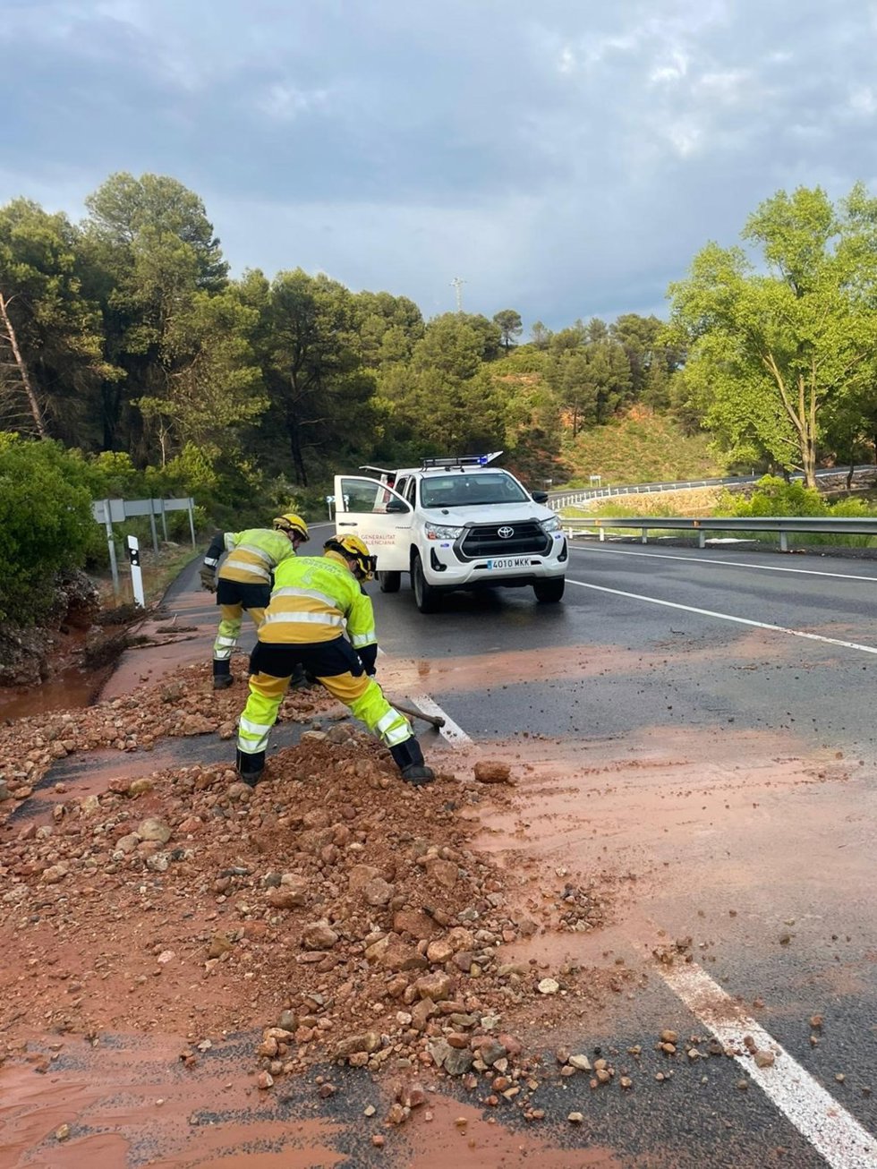Efectivos de la unidad de Bomberos Forestales de Buñol (Valencia) en la N-3 retirando el barro y las piedras acumuladas sobre la calzada por la lluvia.