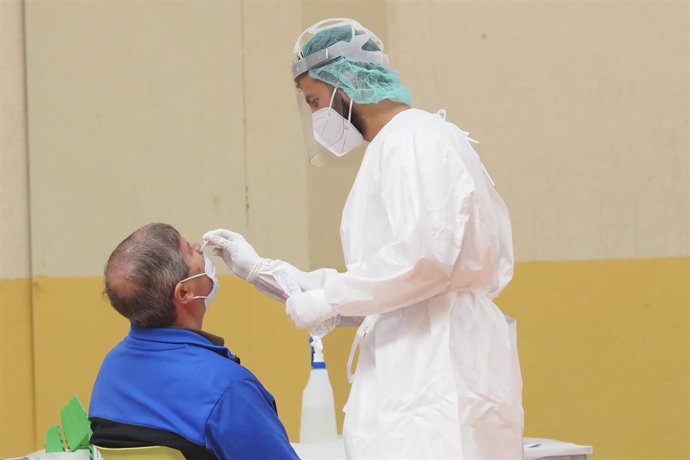 Archivo - Imagen de archivo de una sanitaria toma muestras a un hombre a través de un frotis de nariz durante la realización de test de antígenos.