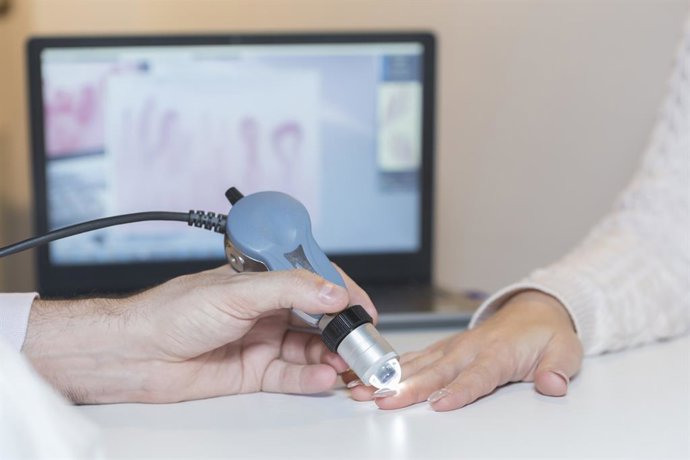 Archivo - Concepto de diagnóstico de esclerosis sistémica: se aprecian las manos de un médico y un paciente junto con la maquinaria de diagnóstico.