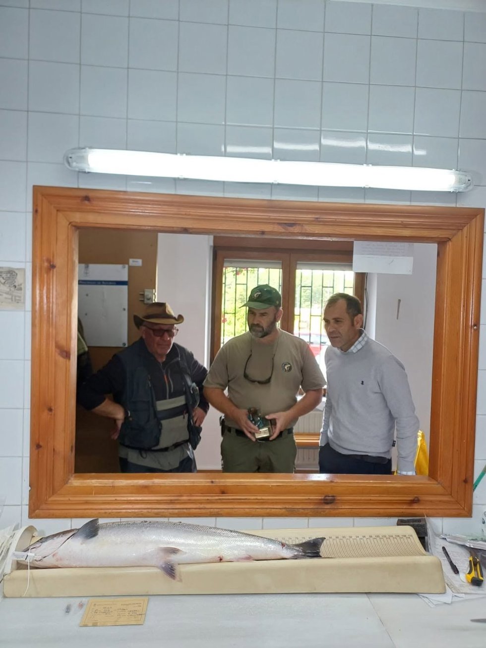 El alcalde de Cangas de Onís, José Manuel González, el presidente de El Esmerillón, Antón Caldevilla, y el pescador Iván Alonso, junto al 'campanu'.