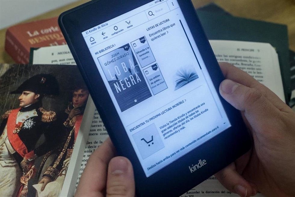 Archivo - Una persona lee en un libro digital sobre libros en papel, a 5 de abril de 2024, en Madrid (España).