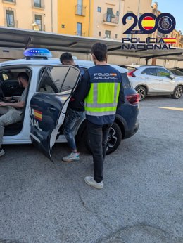 Uno de los expulsados subiendo a un coche patrulla de la Policía Nacional