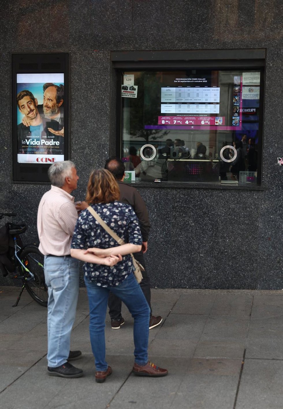 Archivo - Varias personas miran la programación de los cines Callao.