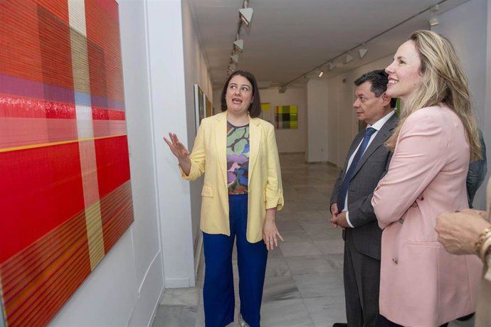 La artista Ángeles Cutillas explica uno de sus cuadros a la vicepresidenta de la Fundación Provincial de Cultura de la Diputación de Cádiz, Vanesa Beltrán.