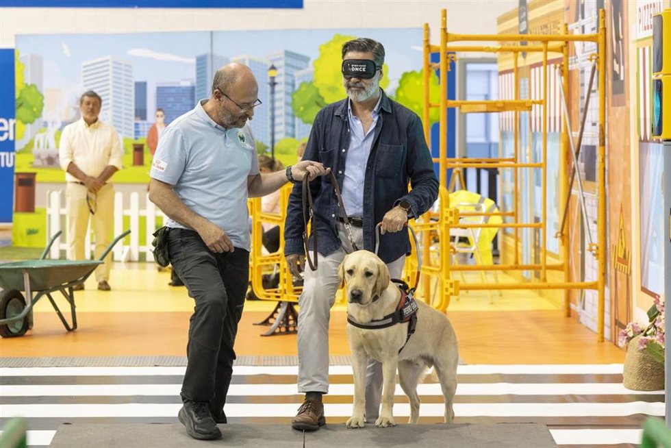 Una persona se pone en la piel de una persona ciega para realizar un recorrido junto a un perro guía durante unra exhibición de la ONCE en Cádiz
