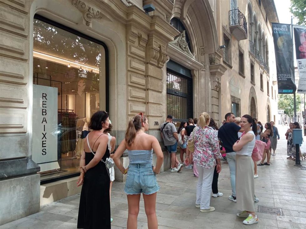 Archivo - Varias personas hacen cola junto a una tienda de ropa en Palma.