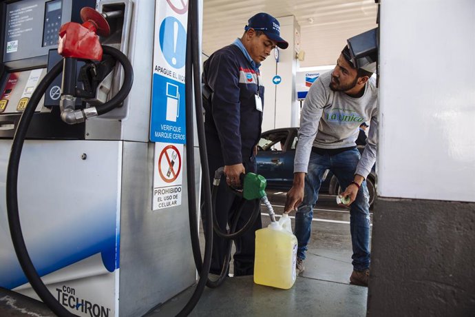 Archivo - A man fills a canister with gasoline at a gas station