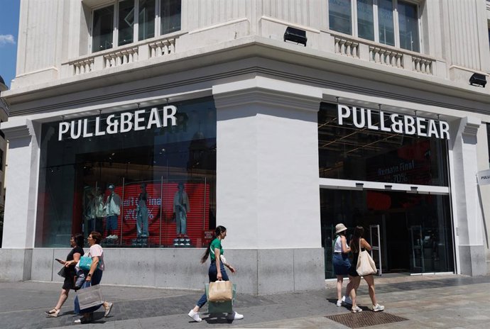 Archivo - Varias personas pasan por delante de una tienda de Pull&Bear