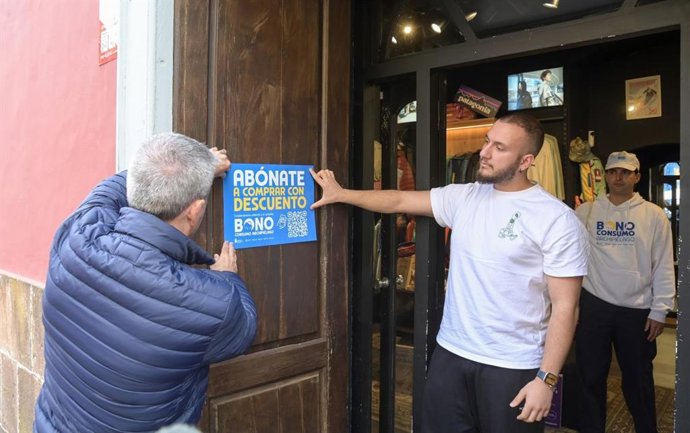 El vicepresidente canario Manuel Domínguez coloca un cartel informativo de la campaña 'Bonos Consumo Archipiélago'