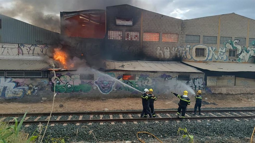 Imagen cedida por Protección Civil de Peligros (Granada) en la que se puede ver a los bomberos trabajando en las tareas de extinción del incendio declarado en una nave industrial de la localidad.
