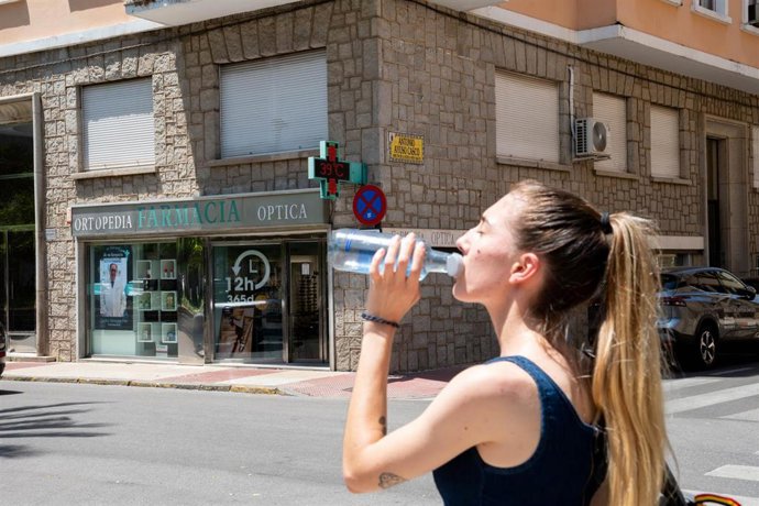 Archivo - Una mujer bebe agua en una calle de Badajoz en una jornada calurosa.