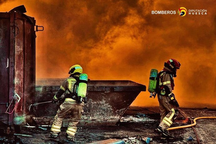 Dos Bomberos de la DPH en medio de las llamas del iniciado este viernes en una planta de reciclado de Fraga.