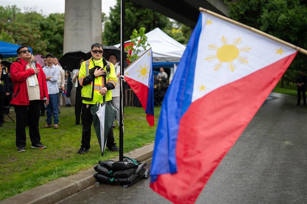 Archivo - La gente se coloca frente a la bandera nacional filipina para escuchar el himno nacional durante el acto conmemorativo en memoria de las víctimas del atentado perpetrado durante el festival del Día de Lapu-Lapu, en Vancouver
