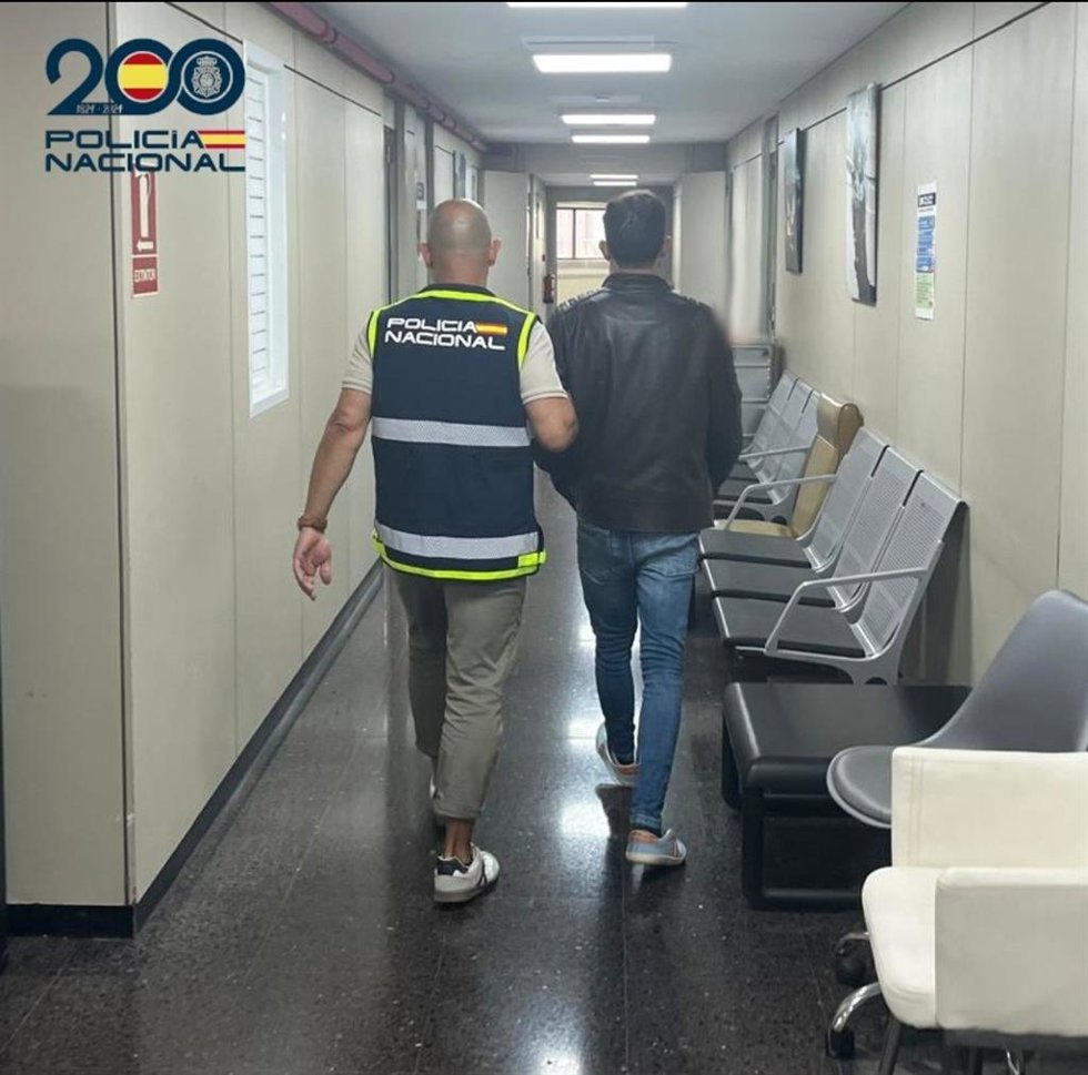 El detenido, de espaldas, escoltado por un agente de la Policía Nacional.