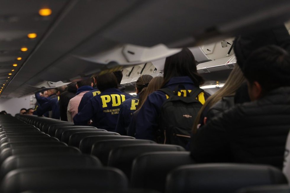 Agentes de la PDI chilena escoltan a migrantes en un vuelo de deportación