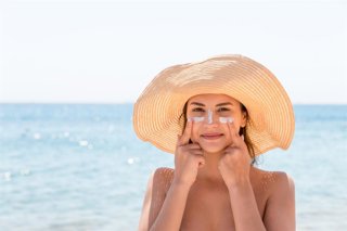 Archivo - Mujer usando protección solar en la playa.