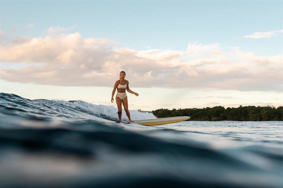 Imagen de una mujer haciendo surf con un bañador de la colección 'Summer 2026' de Decathlon